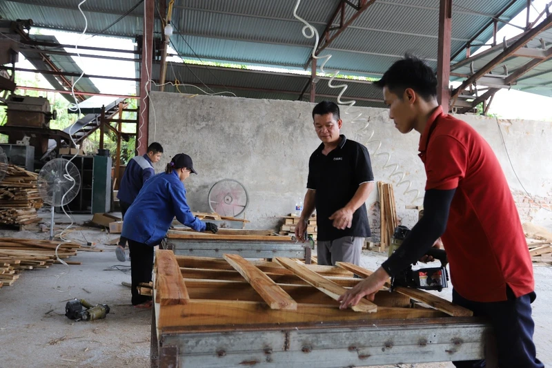 Anh Phùng Bình Minh (người đứng giữa) hướng dẫn công nhân sản xuất gỗ ván thanh xuất khẩu.