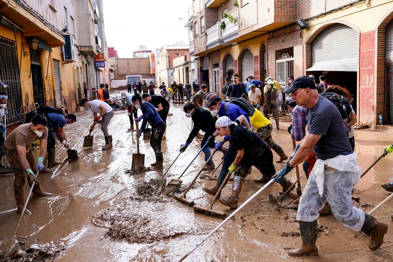 Người dân dọn dẹp bùn sau lũ lụt ở Massanassa, Valencia. Ảnh: Reuters