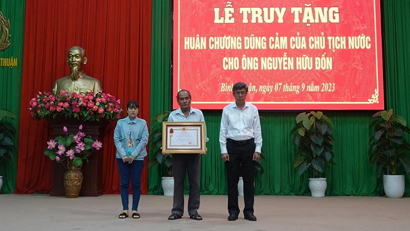 Thân nhân gia đình anh Nguyễn Hữu Đốn (vợ và cha bên trái hình) nhận Huân chương Dũng cảm của Chủ tịch nước truy tặng (Ảnh: CACC)