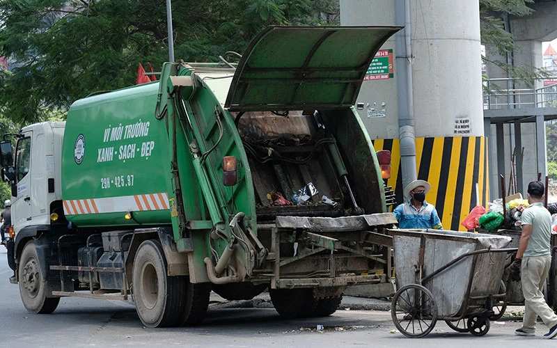 Công nhân Công ty Môi trường đô thị Hà Nội thu gom rác thải ở quận Đống Đa. (Ảnh PHẠM HÙNG)