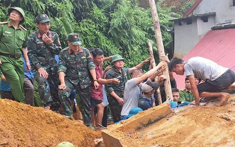 Lực lượng cứu hộ và người dân khẩn trương cứu hộ anh Lương Văn Ba bị mắc kẹt do sạt lở đất. (Ảnh: HẢI CHUNG)