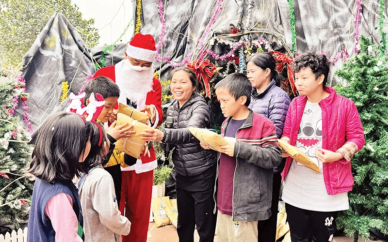 Một thành viên nhóm thiện nguyện đóng vai ông già Noel tặng quà Giáng sinh cho trẻ em ở mái ấm Thánh Tâm.