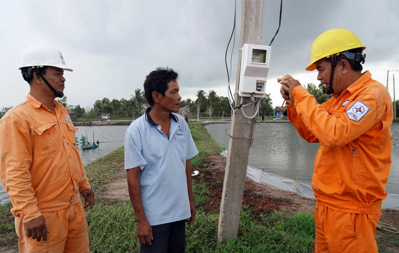 Công nhân Điện lực huyện Mỹ Xuyên, tỉnh Sóc Trăng hướng dẫn, tuyên truyền cho các hộ gia đình sử dụng điện an toàn trong nuôi tôm. (Ảnh: THẾ VĨNH)