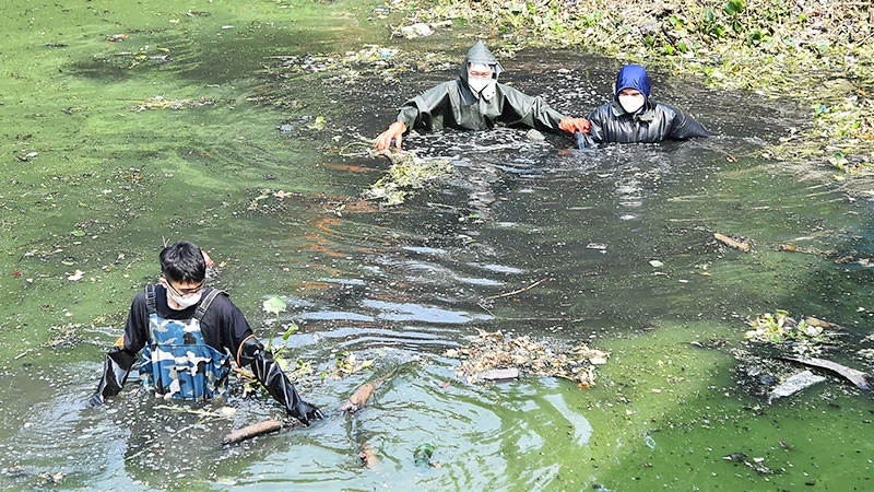 Các thành viên nhóm Hà Nội Xanh thu gom rác thải tại khu vực sông La Khê, chân cầu Mậu Lương, quận Hà Đông. (Ảnh: MỸ HÀ)