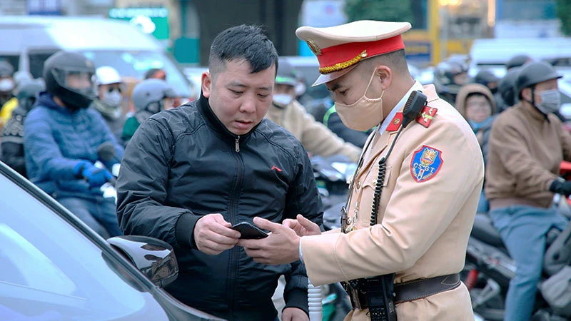 Cán bộ Cảnh sát giao thông, Công an thành phố Hà Nội trao đổi, hướng dẫn người dân tuân thủ pháp luật khi tham gia giao thông. (Ảnh: NAM PHONG)