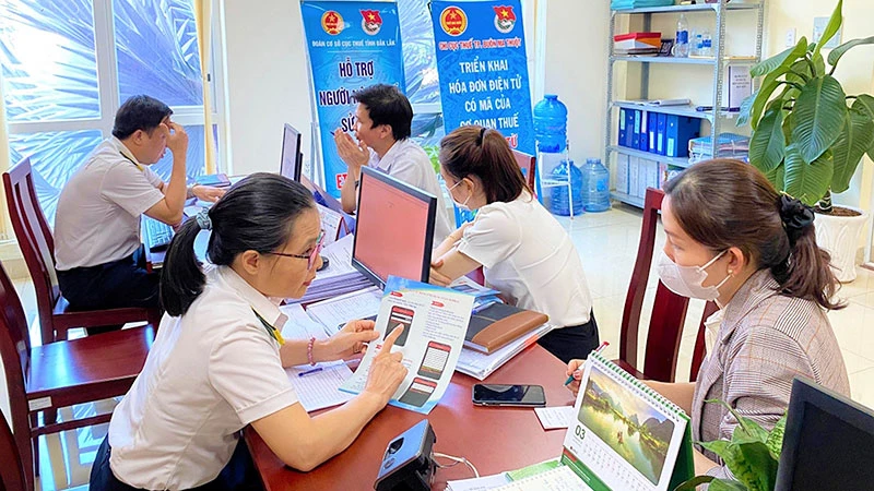 Cán bộ ngành thuế hỗ trợ thủ tục nộp thuế cho hộ kinh doanh tại thành phố Buôn Ma Thuột (tỉnh Đắk Lắk). (Ảnh: KHÁNH HUYỀN)