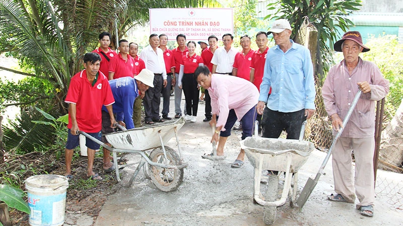 Thành viên Hội Chữ thập đỏ xã Đông Thạnh, thị xã Bình Minh (tỉnh Vĩnh Long) tham gia vá đường giao thông nông thôn. (Ảnh: BÁ DŨNG)