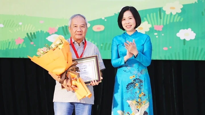 Bà Vũ Việt Trang - Tổng Giám đốc TTXVN trao Giải thưởng Lớn - Hiệp sĩ Dế Mèn cho nhà văn Trần Đức Tiến.