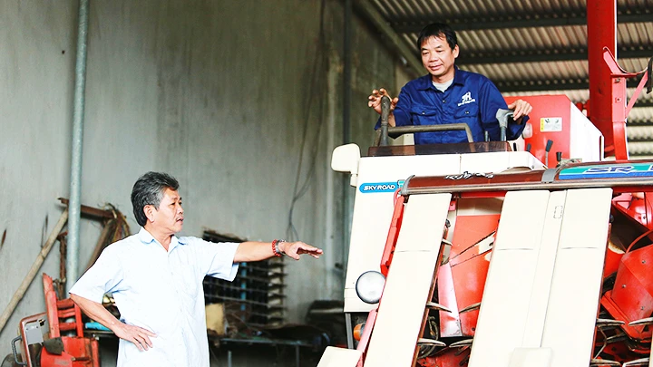 Ông Hùng (trái) hướng dẫn thợ kiểm tra máy. 