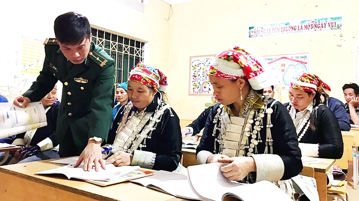 Thiếu tá Đinh Thái Đạt, Đồn Biên phòng A Mú Sung dạy xóa mù chữ cho bà con dân tộc Dao ở thôn Y Giang, xã A Mú Sung (Bát Xát, Lào Cai). 