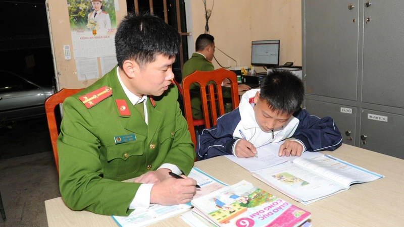 Thượng úy La Tuấn Anh, Công an xã Niêm Sơn, huyện Mèo Vạc tranh thủ dạy cháu Ly Mí Hồng học bài.