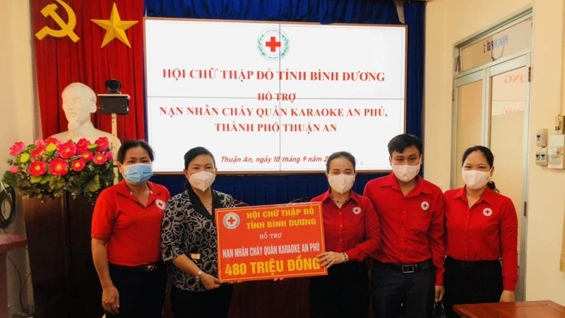 Chủ tịch Hội Chữ thập đỏ tỉnh Bình Dương Nguyễn Thị Lệ Trinh (thứ ba từ phải sang) trao tiền hỗ trợ nạn nhân vụ cháy cho lãnh đạo Ủy ban nhân dân thành phố Thuận An.