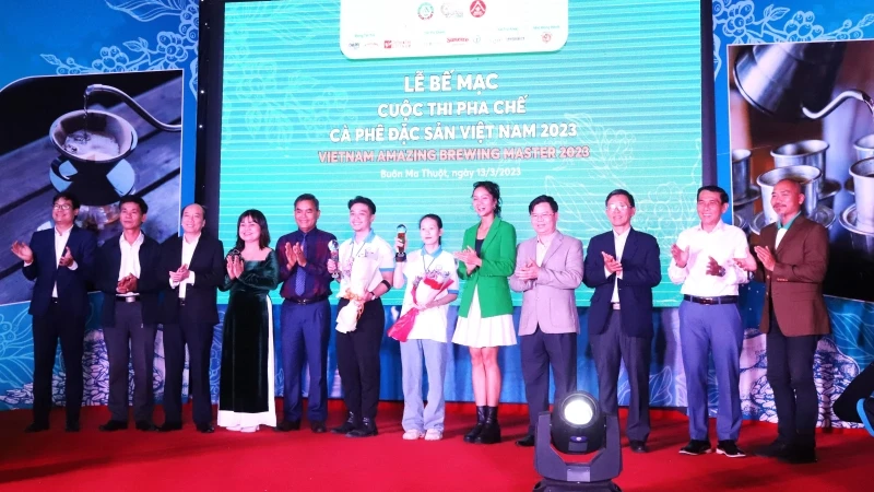 Hai thí sinh đoạt giải Nhất Cuộc thi pha chế cà-phê đặc sản Việt Nam năm 2023 Trương Thị Thiện và Phạm Ngọc Thạch chụp hình với các đồng chí lãnh đạo tỉnh Đắk Lắk và Ban tổ chức cuộc thi tại lễ bế mạc.