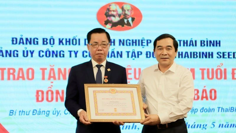 Phó Bí thư Thường trực Tỉnh ủy Thái Bình Nguyễn Tiến Thành (bên phải) trao Huy hiệu 50 năm tuổi Đảng cho đồng chí Trần Mạnh Báo.