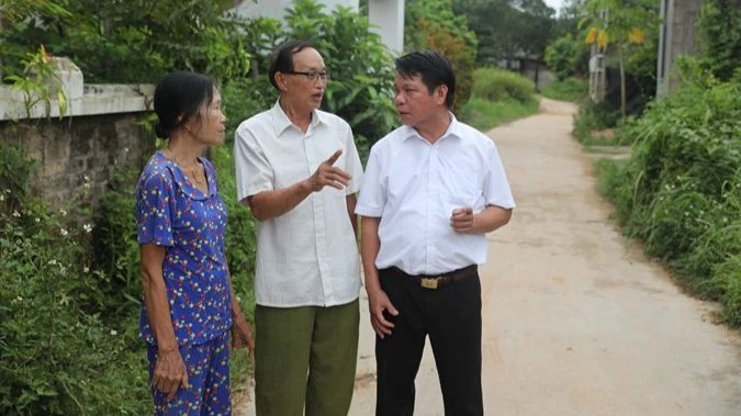 Ông Ma Hữu Khang (giữa) trao đổi về công tác vận động nhân dân hiến đất làm đường.
