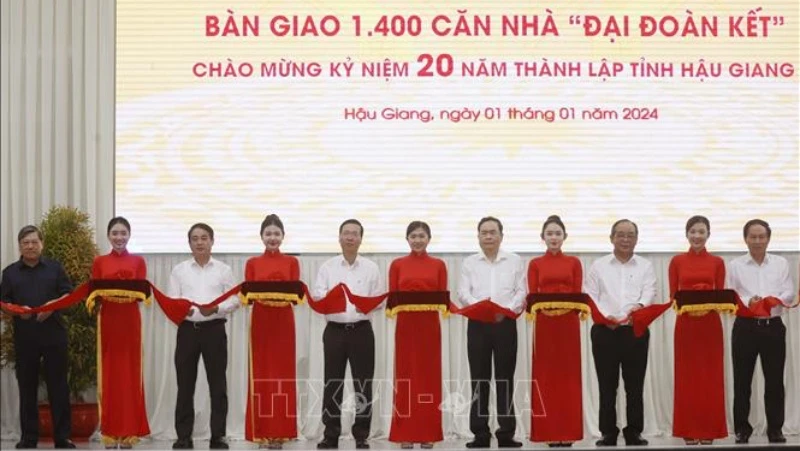 Chủ tịch nước Võ Văn Thưởng cùng các đại biểu thực hiện nghi thức bàn giao 1.400 căn nhà Đại đoàn kết tặng hộ nghèo Hậu Giang. (Ảnh: Thống Nhất/TTXVN)