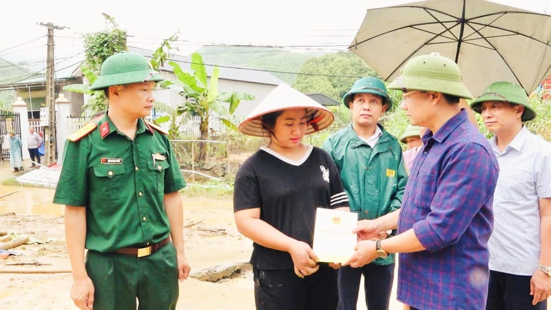 Chủ tịch Ủy ban nhân dân huyện Văn Yên Hà Đức Anh trao hỗ trợ cho người dân bị thiệt hại đổ nhà do mưa bão. (Ảnh: THANH SƠN)