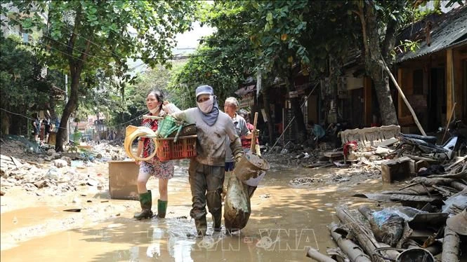 Người dân lội bùn khi di chuyển trên 2 tuyến phố Thanh Niên và Trần Hưng Đạo (thành phố Yên Bái, tỉnh Yên Bái), chiều 14/9. (Ảnh: Tuấn Anh/TTXVN)