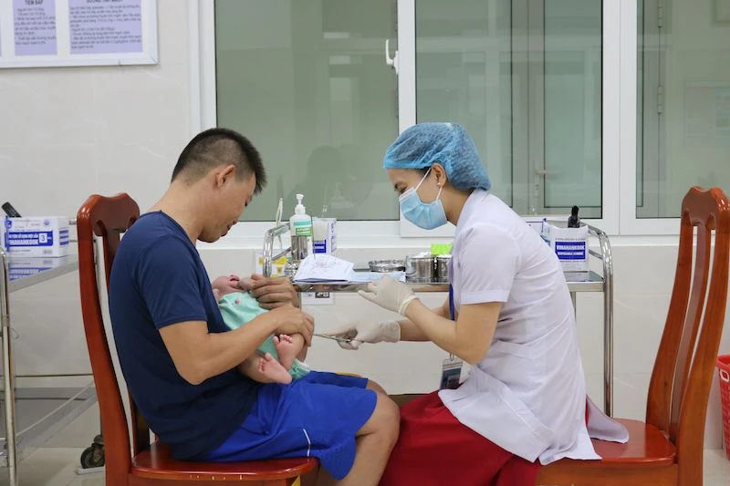 Người dân đưa trẻ đến tiêm vaccine tại Trung tâm kiểm soát bệnh tật TP Đà Nẵng. (Ảnh HUỲNH LÊ)