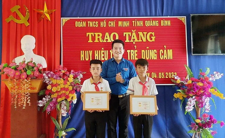 Đại diện lãnh đạo Tỉnh Đoàn Quảng Bình trao tặng huy hiệu cho 2 học sinh.