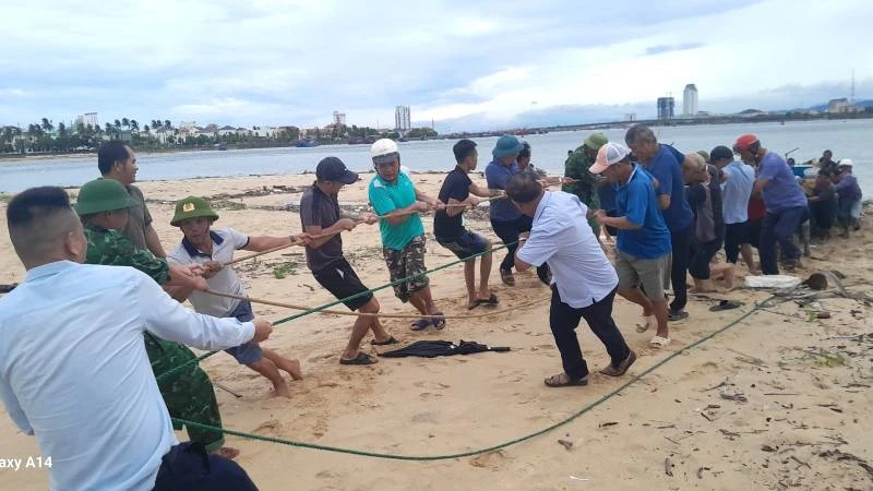 Bộ đội Biên phòng Quảng Bình cùng người dân Đồng Hới phối hợp kéo chiếc tàu câu mực bị chìm lên bờ. 