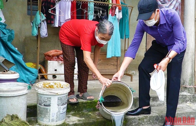 Cán bộ y tế ở Quảng Bình hướng dẫn người dân xử lý dụng cụ chứa nước để diệt loăng quăng.