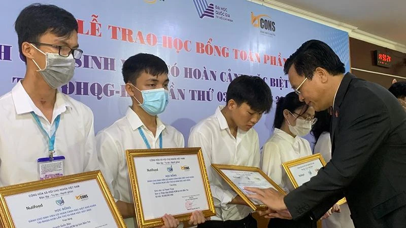 PGS, TS Nguyễn Đình Tứ, Giám đốc Quỹ Phát triển Đại học Quốc gia Thành phố Hồ Chí Minh trao học bổng cho các em sinh viên.