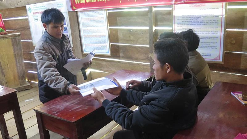 Chính quyền xã Măng Cành, huyện Kon Plông phát Sổ tay phổ biến kiến thức về động đất cho người dân.