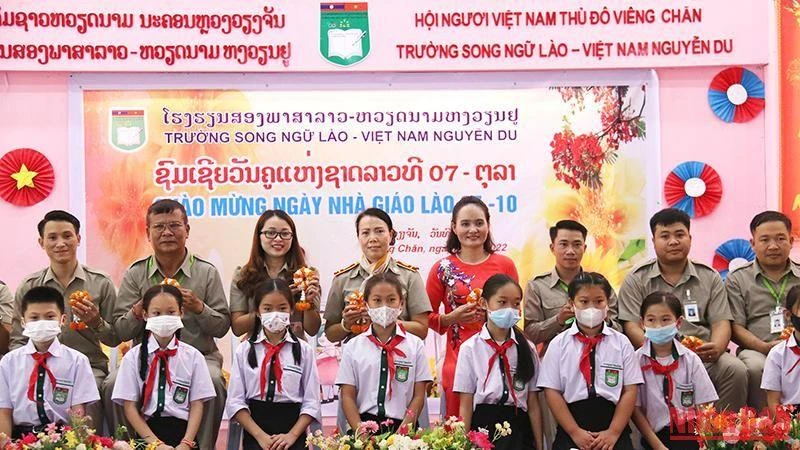 Các em học sinh Trường song ngữ Lào-Việt Nam Nguyễn Du tặng hoa tri ân các thầy, cô giáo nhân Ngày nhà giáo quốc gia Lào. (Ảnh: Hải Tiến)