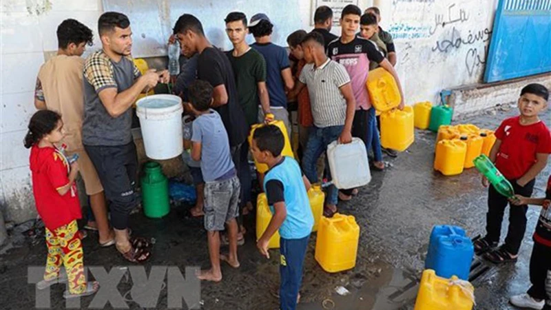Người dân Palestine xếp hàng chờ lấy nước tại thành phố Khan Younis, miền nam Dải Gaza. (Ảnh: THX/TTXVN)