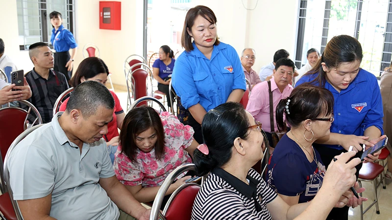 Các thành viên tổ công nghệ số cộng đồng phường Minh Xuân, thành phố Tuyên Quang hướng dẫn người dân cài đặt ứng dụng số.