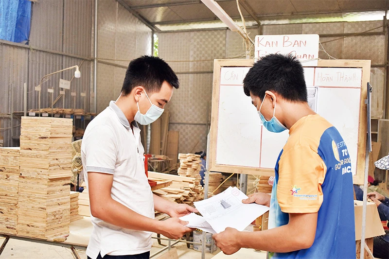 Vũ Anh Văn (bên trái) trao đổi với nhân viên về sản phẩm mới làm từ cây tre.