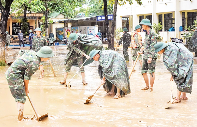 Các chiến sĩ Bộ Tư lệnh Quân khu 4 dọn bùn đất tại Trường tiểu học và Trung học cơ sở Cam Tuyền, huyện Cam Lộ (Quảng Trị). (Ảnh NGUYỄN DO) 