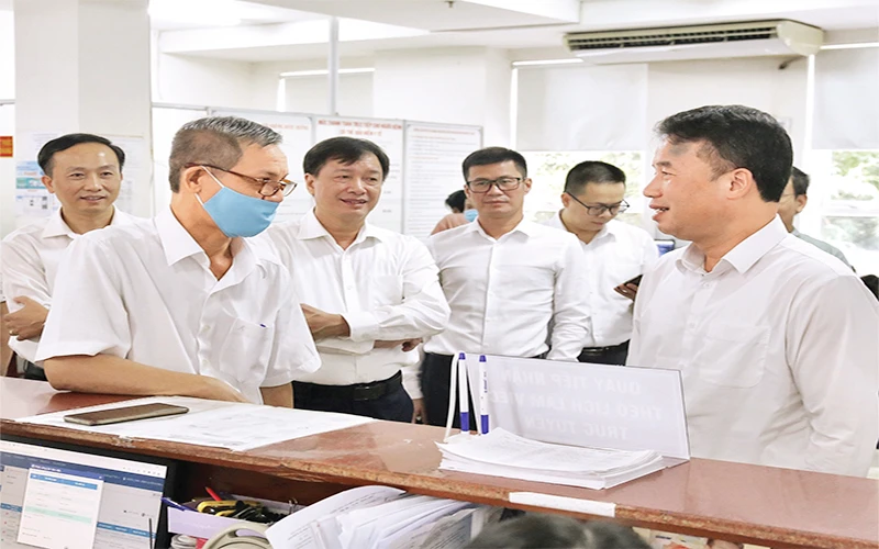 Tổng Giám đốc Bảo hiểm xã hội Việt Nam Nguyễn Thế Mạnh (ngoài cùng, bên phải) trao đổi với người dân đến làm việc tại Bảo hiểm xã hội Thành phố Hồ Chí Minh.