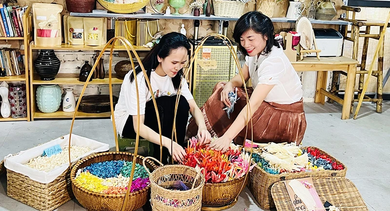 Chị Trang Phương (bên phải) đào tạo nghề cho bạn trẻ tại xưởng hoa khô Xavia (Hà Nội).