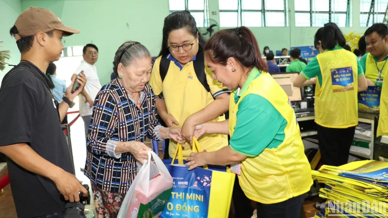 Các tình nguyện viên hỗ trợ một cụ bà mua sắm tại siêu thị 0 đồng.