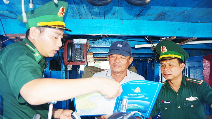 Cán bộ Đồn Biên phòng Tam Quan Nam tuyên truyền pháp luật cho ngư dân trước khi xuất bến. 