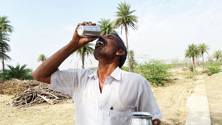 Ông Sharma uống nước từ một giếng ngầm trong làng. Ảnh: THE GUARDIAN