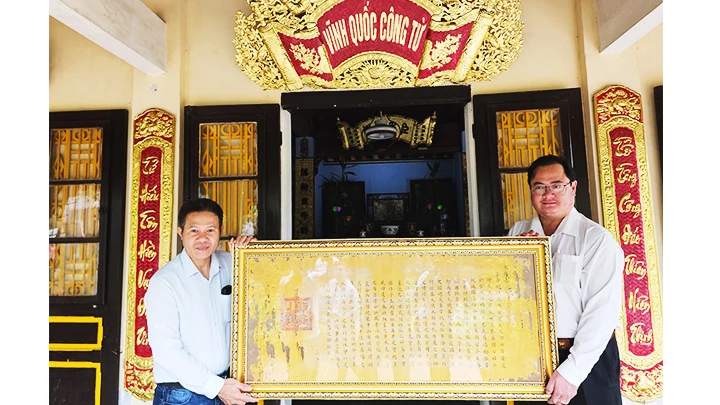 Anh Nguyễn Hữu Hoàng (trái) tặng lại bức sắc phong quý cho thủ từ phủ Vĩnh Quốc Công, TP Huế.