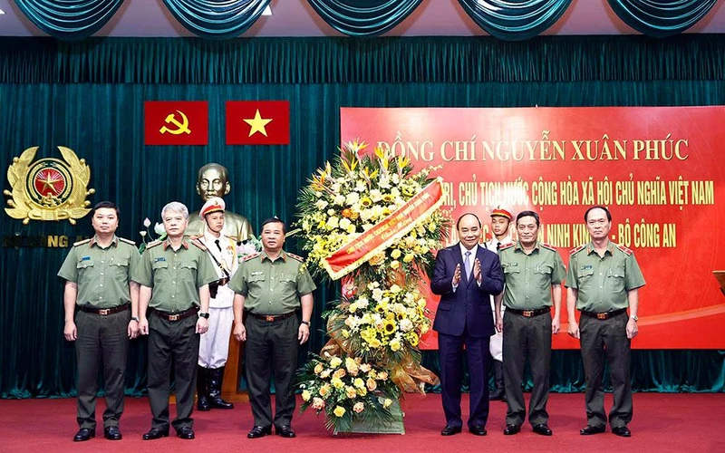 Chủ tịch nước Nguyễn Xuân Phúc tặng hoa Cục An ninh kinh tế nhân kỷ niệm 77 năm Ngày truyền thống lực lượng Công an nhân dân. (Ảnh: TTXVN)