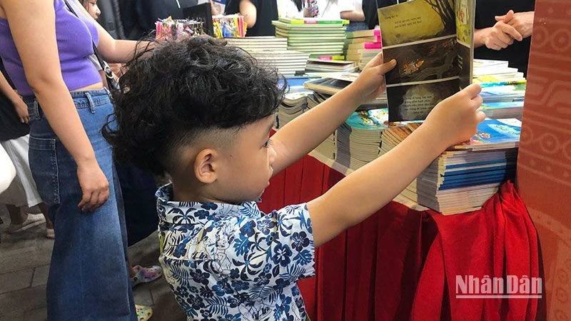 Em bé say sưa xem sách tại Hội sách Hà Nội 2022.