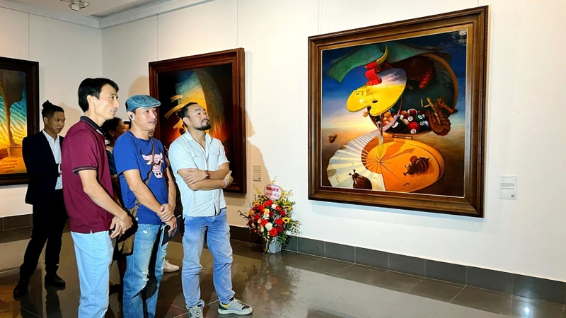 Hoạ sĩ Lê Thanh Bình (áo đỏ) giới thiệu tác phẩm của mình đến người xem tại triển lãm “Ký ức xuyên không” chiều 18/10. 