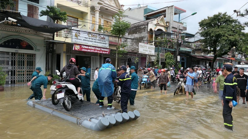 Lực lượng dân quân phường Minh Khai, thành phố Hà Giang đưa người dân qua đoạn đường ngập úng.