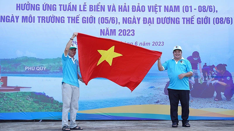 Đại diện Sở Tài nguyên và Môi trường Bình Thuận trao cờ Tổ quốc cho ngư dân đảo Phú Quý. (Ảnh: Hữu Tri)