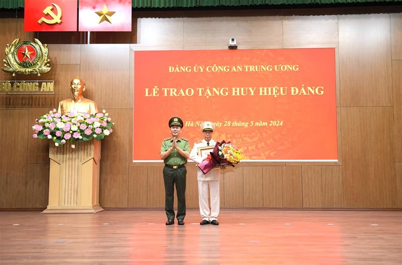 Thứ trưởng Trần Quốc Tỏ trao Giấy chứng nhận, gắn Huy hiệu và tặng hoa chúc mừng Thượng tướng Bùi Văn Nam. (Ảnh: Bộ Công an)