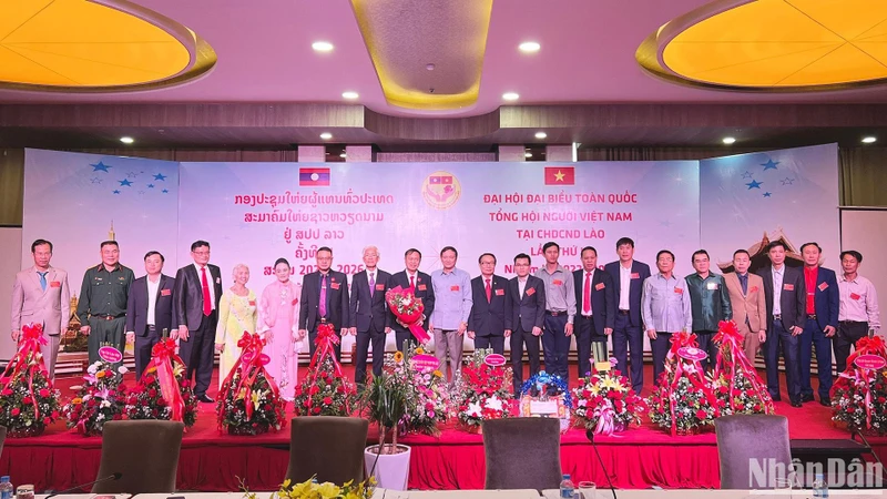 Đại sứ Nguyễn Bá Hùng tặng hoa chúc mừng Chủ tịch và Ban Chấp hành khóa III Tổng hội người Việt Nam tại Lào. (Ảnh: Trịnh Dũng)
