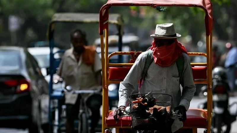 Người dân đội mũ và khăn để tránh nắng nóng tại New Delhi, Ấn Độ. (Ảnh: AFP/TTXVN)