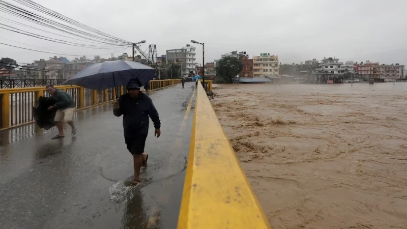 Người dân đi qua cầu bắc qua sông Bagmati tại Kathmandu. Phía kế bên có thể thấy mực nước đang dâng rất cao. (Ảnh: Reuters)