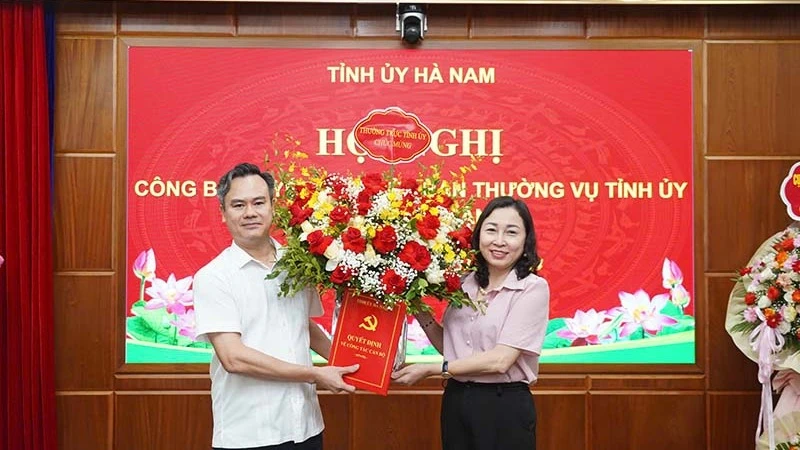 Đồng chí Phó Bí thư Thường trực Tỉnh ủy Đinh Thị Lụa trao quyết định và tặng hoa chúc mừng đồng chí Trần Nguyễn Hiền Anh.