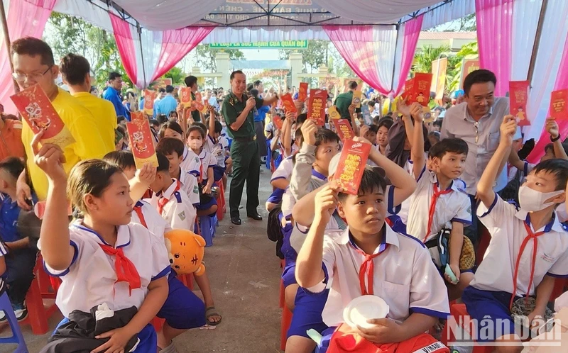 Học sinh biên giới tham dự chương trình chợ Tết yêu thương và nhận bao lì xì từ tay các bộ, chiến sĩ Đồn Biên phòng Sông Trăng, Long An trao. 